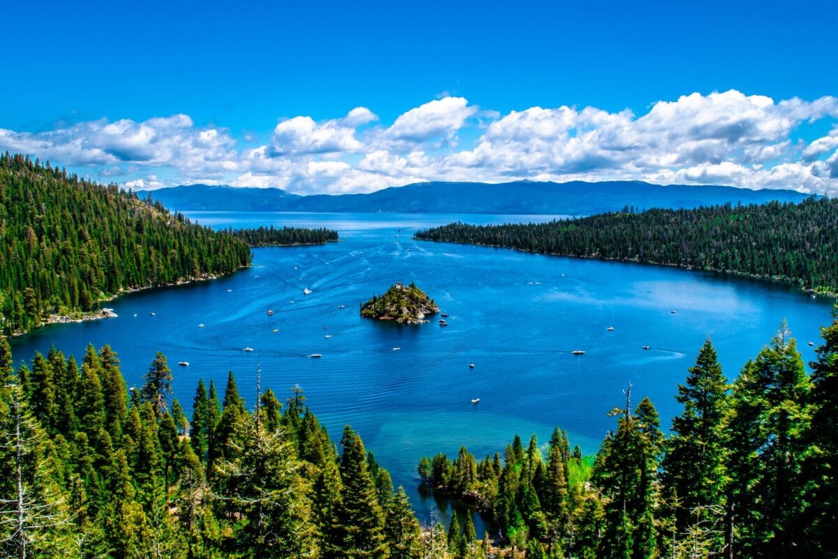Aerial view of Emerald Bay South Lake Tahoe featuring Fannette Island, turquoise water, and dense pine forest under a blue sky.