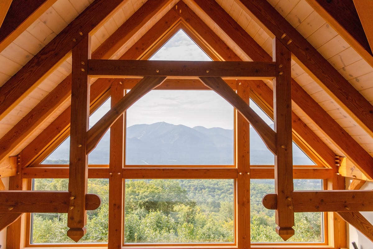 A rustic wooden interior featuring large windows framing a scenic mountain view.