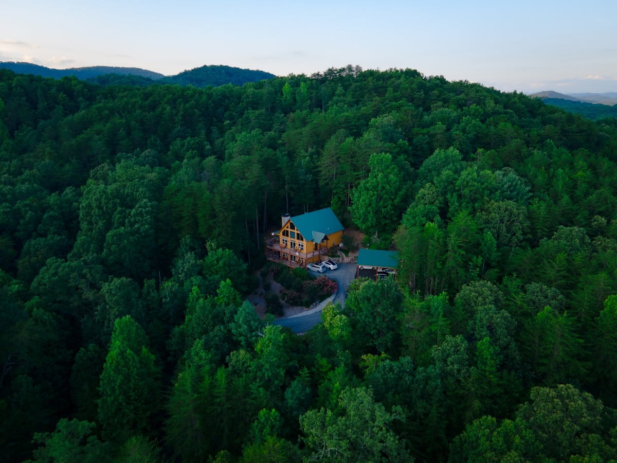 Smoky Mountain Cabins: How to Choose the Right One for Families 5 A serene aerial view of a cabin nestled within dense green forests, showcasing nature's tranquility in Cleveland, Georgia.