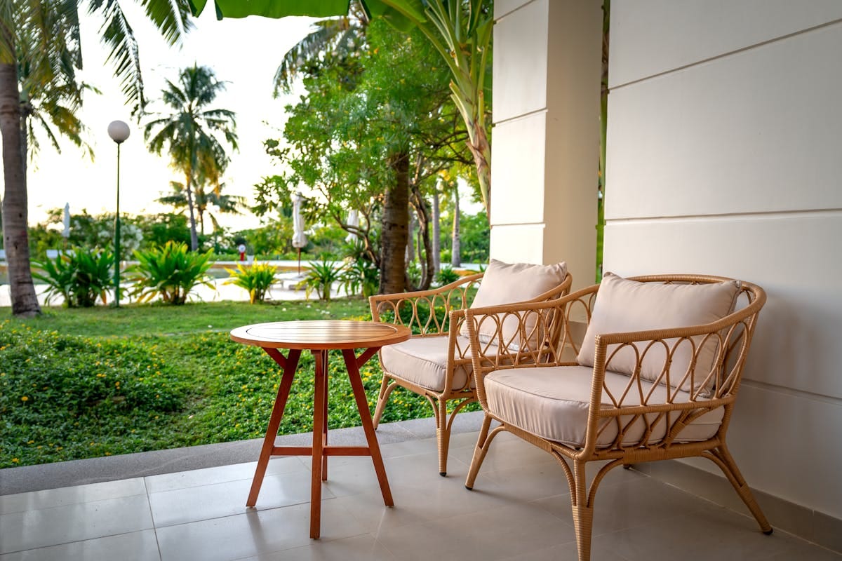 A serene patio setup with rattan chairs overlooking a lush tropical garden, perfect for relaxation.