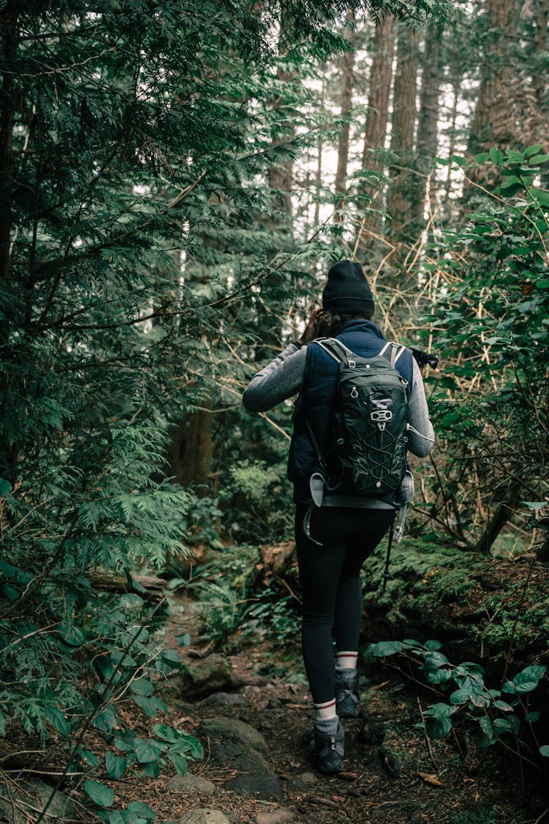 A woman hiking through a lush forest trail, enjoying nature's beauty.