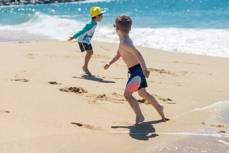 Kids in Hawaii enjoying a sunny day playing at the beach by the ocean.